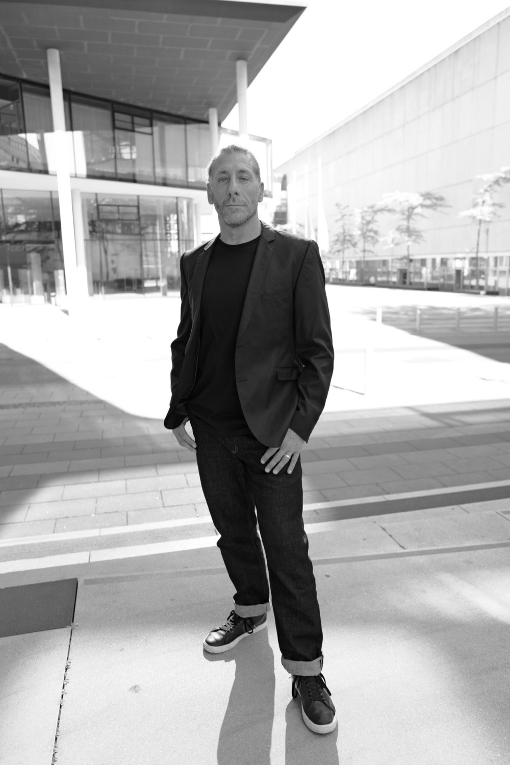 Schwarzweiß-Business-Portrait in Sakko und Jeans vor moderner Glasarchitektur in Aachen