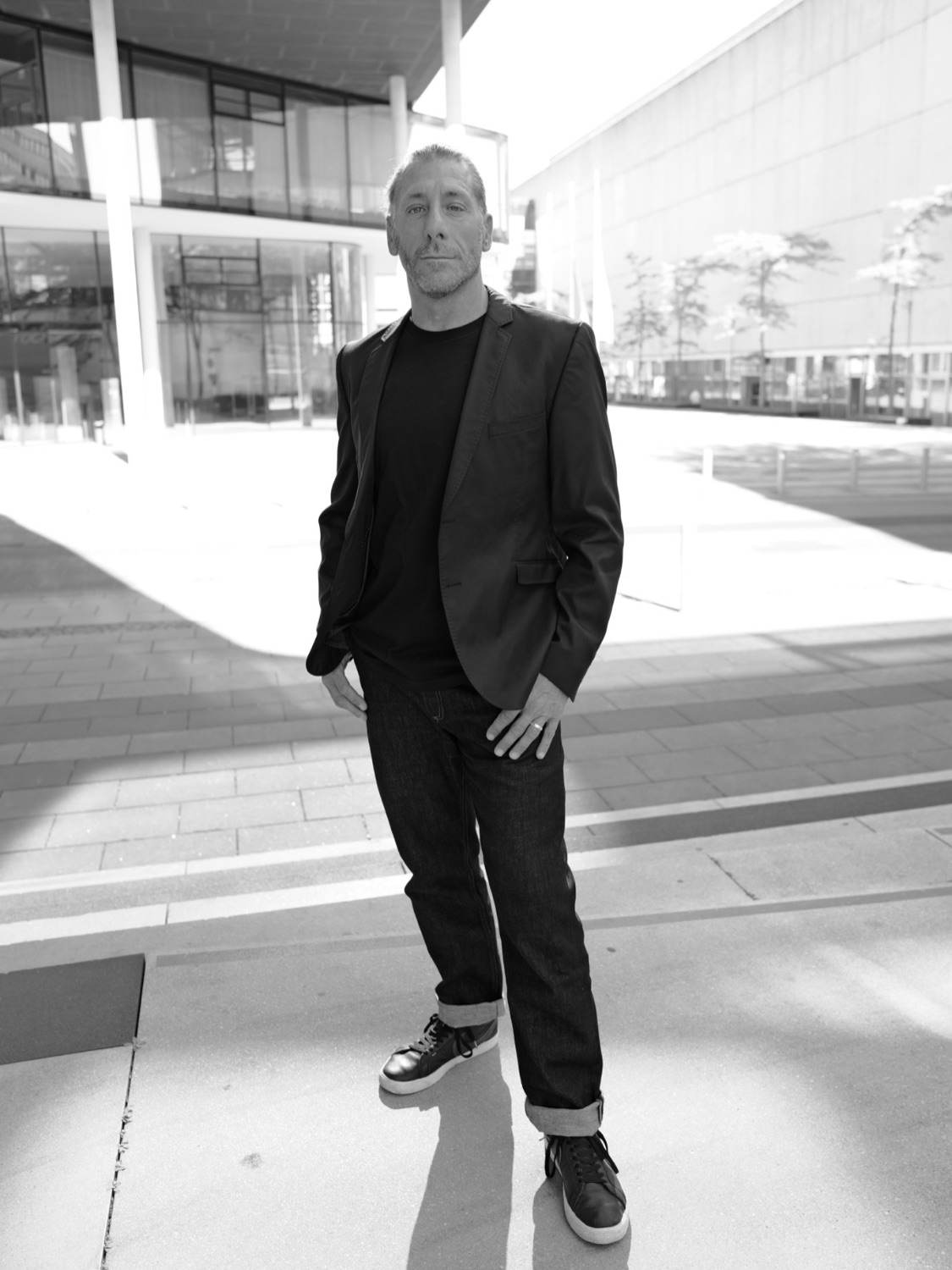Business-Portrait outdoor in Aachen: Mann in Sakko und Jeans vor moderner Glasarchitektur – Anna Wawra Fotografie