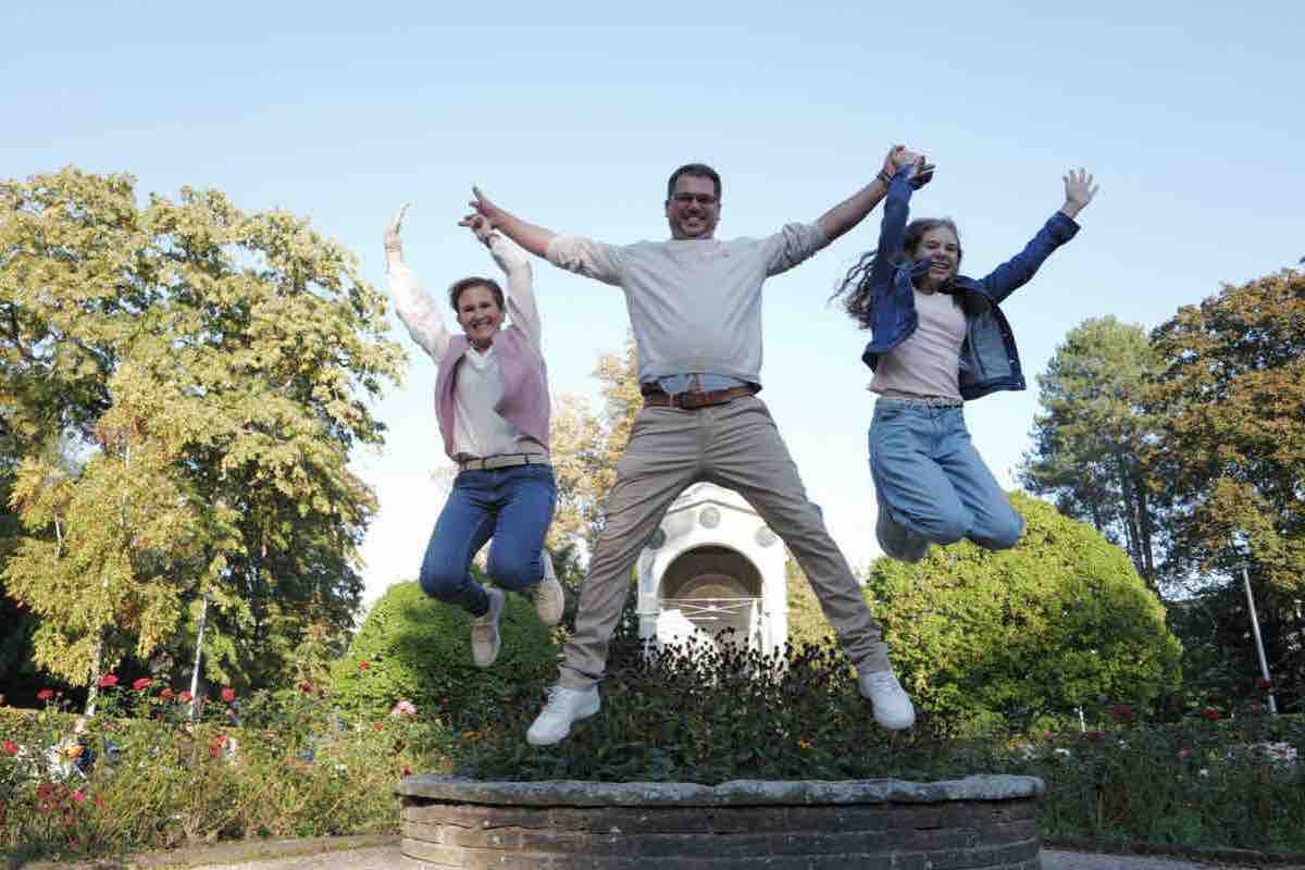Familie springt im Herbst gemeinsam von einer Mauer im Rosengarten in Aachen