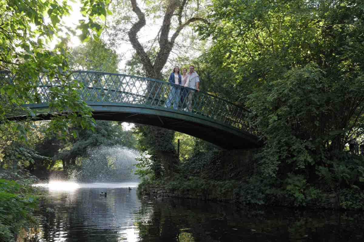Familie auf der grünen Brücke über dem Weiher mit Fontäne im Kurgarten Aachen