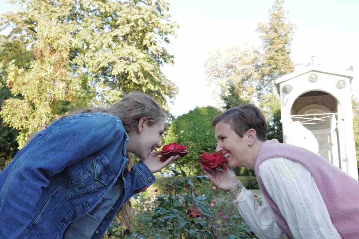 Mutter und Tochter riechen an roten Rosen im Rosengarten im Stadtpark Aachen
