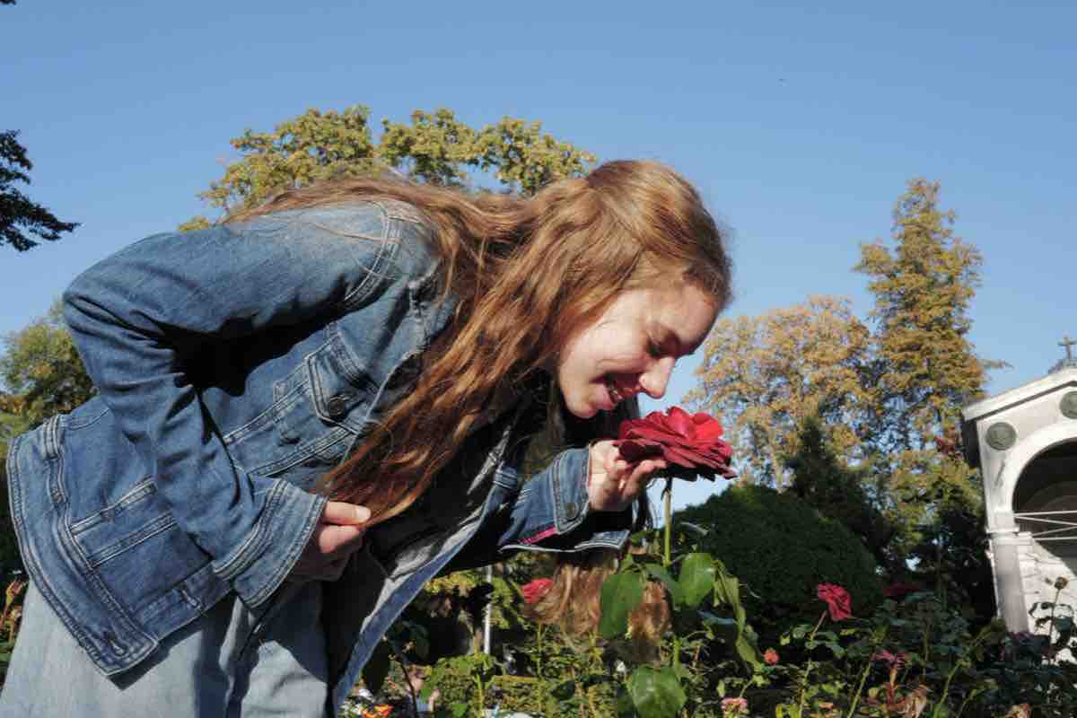 Tochter riecht lachend an einer roten Rose