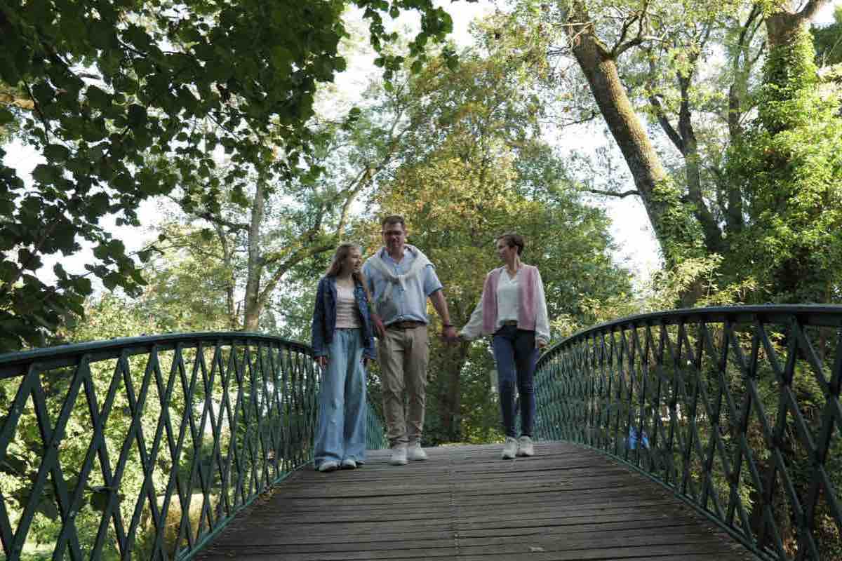Familie läuft gemeinsam über die Brücke im Stadtpark