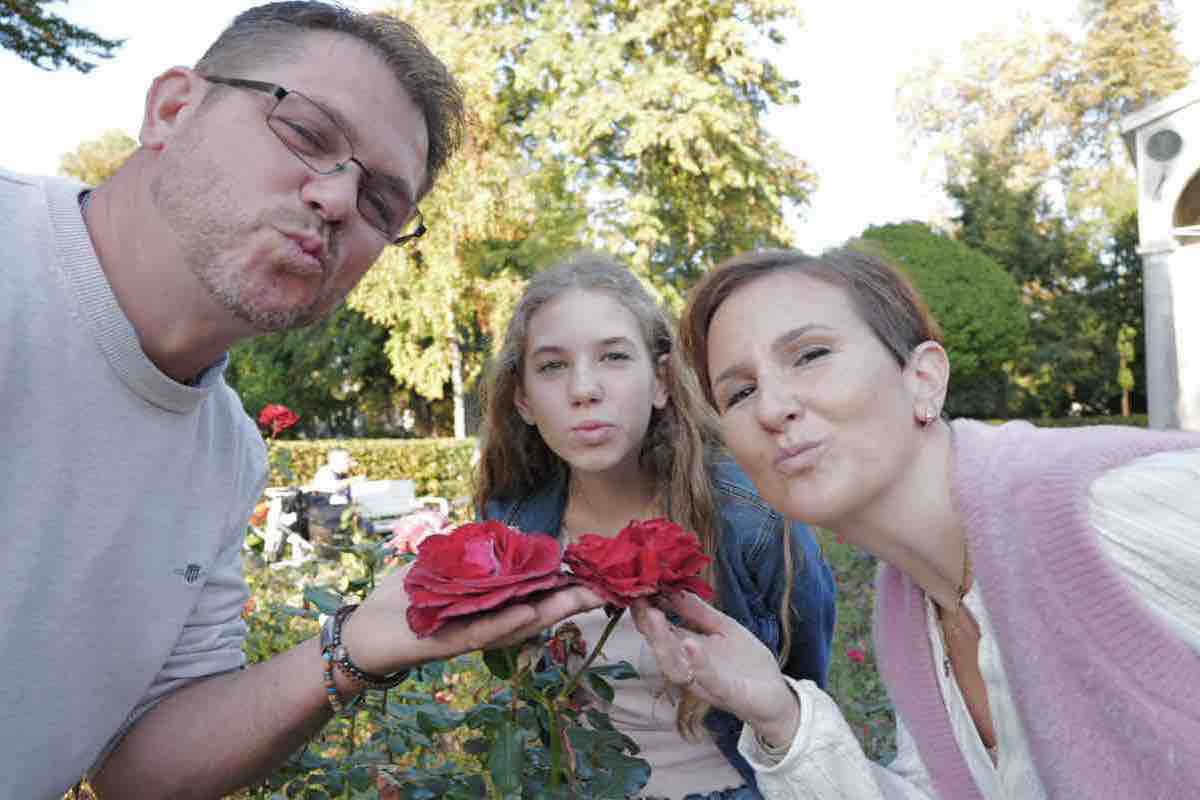 Familie macht einen Kussmund hinter zwei roten Rosen