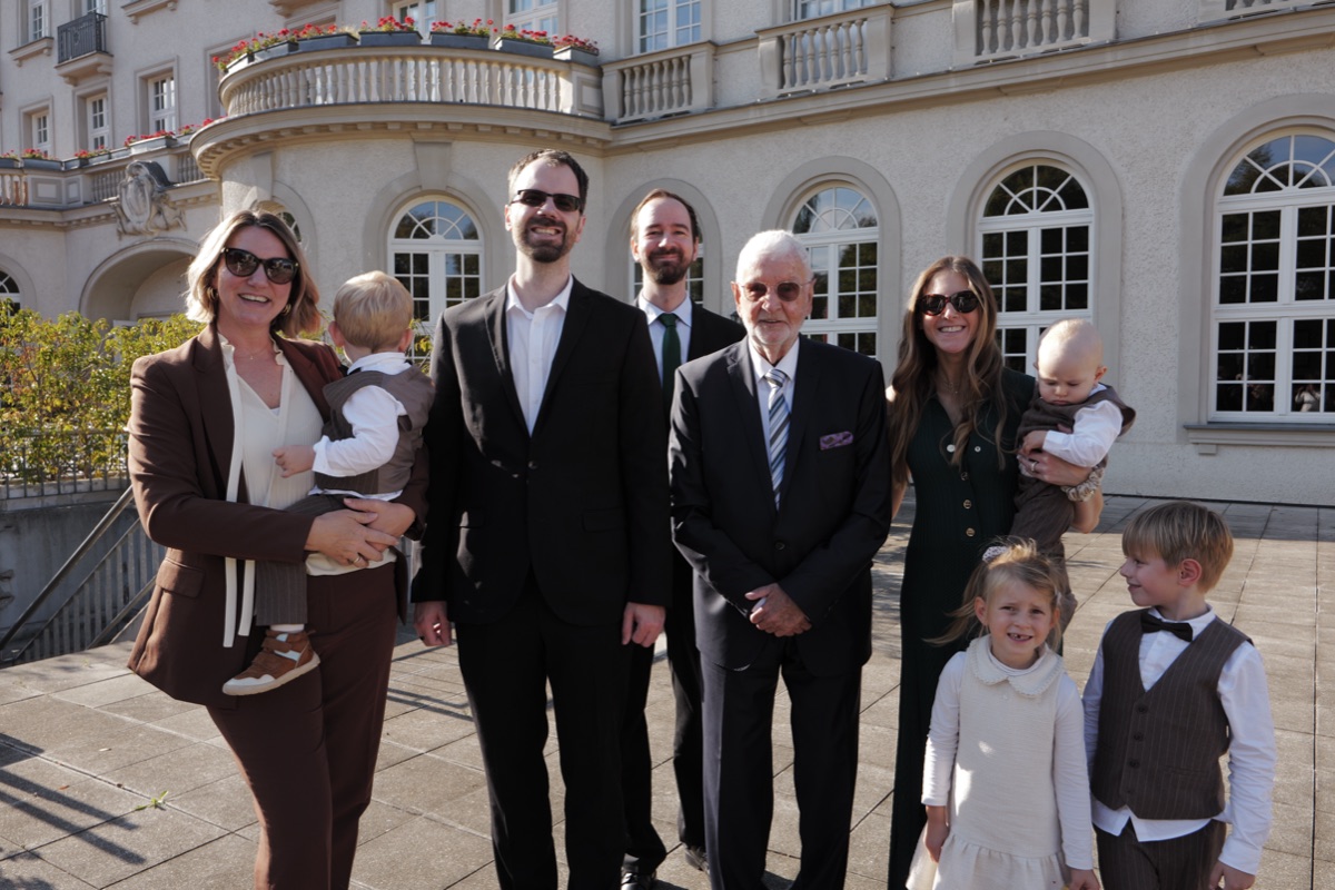 Familie mit Kindern auf der sonnigen Terrasse vor dem Hotel
