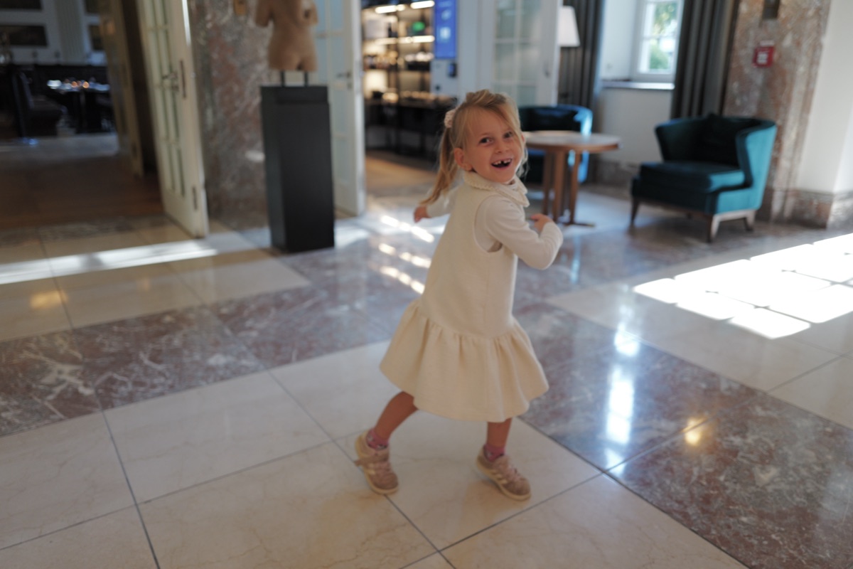 Mädchen im hellen Kleid läuft durch die Hotelhalle