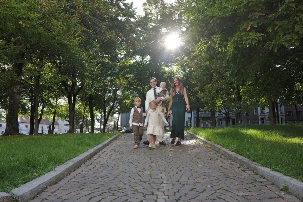 Familie spaziert im Gegenlicht eine Allee entlang